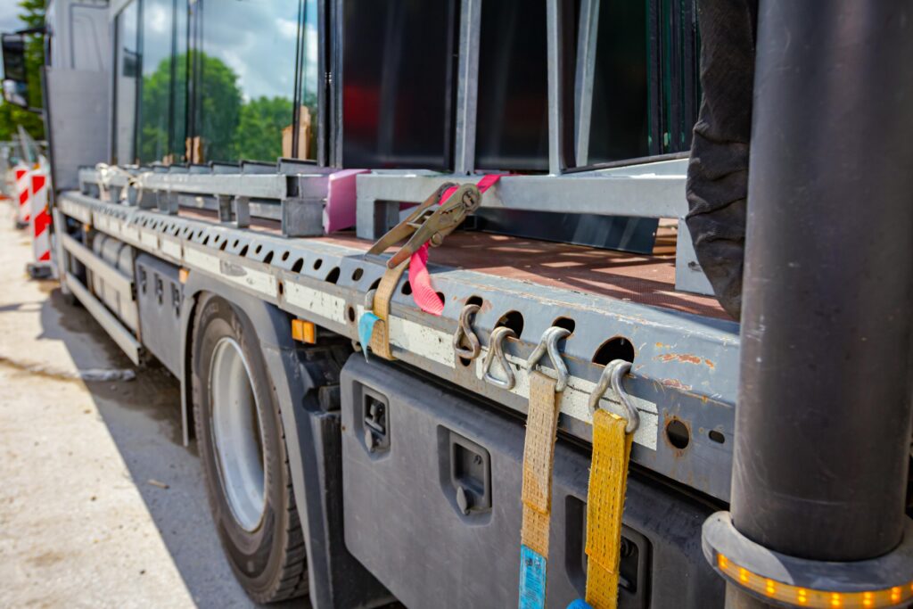 Flatbed commercial truck with cargo secured by tie-down straps on a highway
