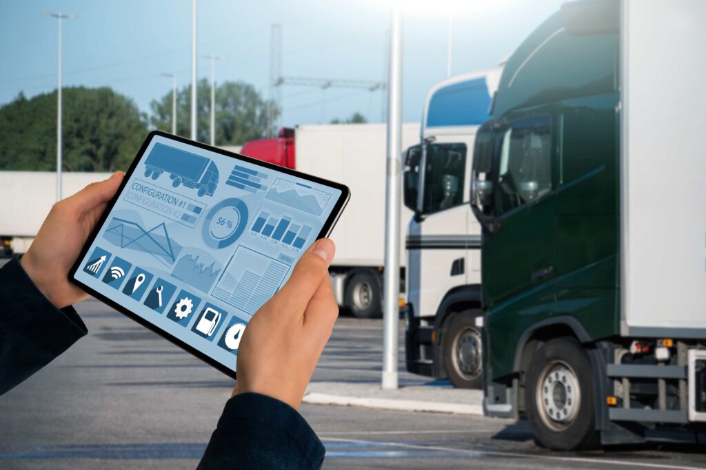 Fleet management dashboard on a tablet displaying vehicle data with commercial trucks in the background